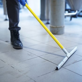 Close up of mop cleaning industrial plant floor.