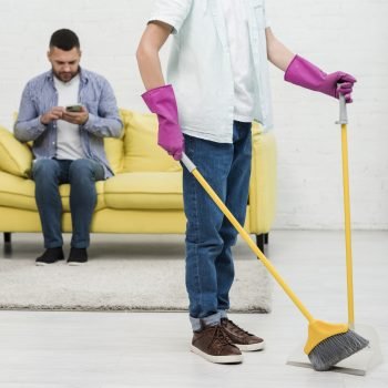 son-using-broom-while-father-checks-phone